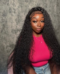 a black woman wearing a pink shirt with long curly hair